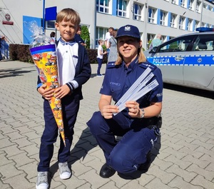 zdjęcie kolorowe: policjantka podczas pamiątkowego zdjęcia z chłopcem trzymającym tytę