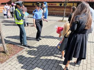 zdjęcie kolorowe: funkcjonariuszki Straży Miejskiej i Inspektoratu Transportu Drogowego w rozmowie z pierwszoklasistami przed budynkiem szkoły