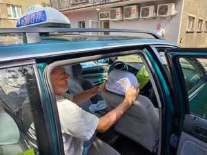 zdjęcie kolorowe: taksówkarz zakładający pokrowiec profilaktyczny na zagłówek samochodowy