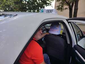 zdjęcie kolorowe: kierujący taksówką zakładający pokrowiec profilaktyczny na zagłówek samochodowy