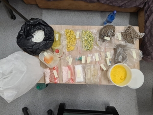 zdjęcie kolorowe: stół na którym zebrano różnego rodzaju narkotyki ujawnione w mieszkaniu zatrzymanego mężczyzny