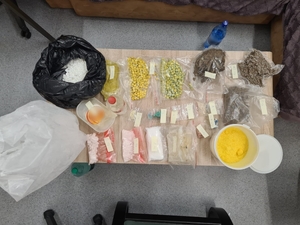 zdjęcie kolorowe: stół na którym zebrano różnego rodzaju narkotyki ujawnione w mieszkaniu zatrzymanego mężczyzny