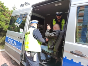 zdjęcie kolorowe: dwóch policjantów katowickiej drogówki w policyjnym furgonie z mężczyzna zatrzymanym za usiłowanie wręczenia łapówki