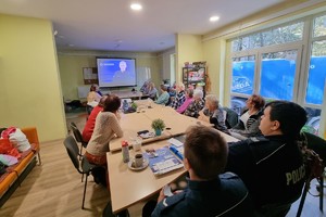 Zdjęcie kolorowe przedstawia policjantów wykorzystujących materiały multimedialne podczas spotkania z seniorami.