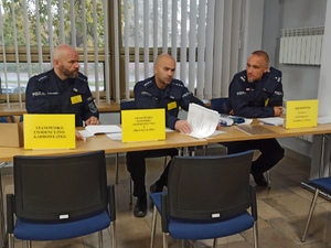 zdjęcie kolorowe: trzech policjantów weryfikujących stawiennictwo rezerwistów na ćwiczenia