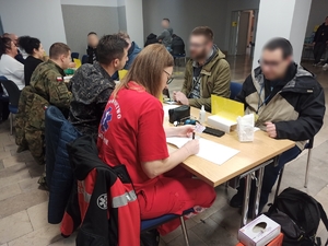 zdjęcie kolorowe: rezerwiści przy stanowisku konsultacji medycznych w czasie przyjęcia na ćwiczenia