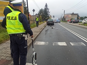 zdjęcie kolorowe: dwóch policjantów ruchu drogowego wykonujący pomiary na miejscu zdarzenia