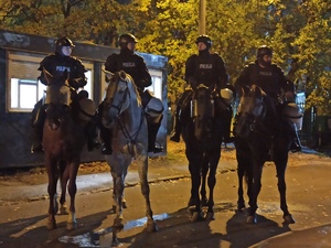 zdjęcie kolorowe: 4 policjantów na koniach służbowych przed stadionem GKS-U