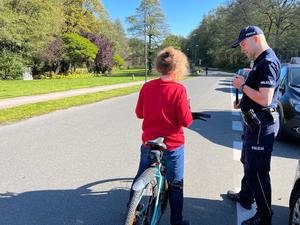 zdjęcie kolorowe: policjant rozmawiający z rowerzysta o bezpieczeństwie