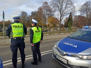 zdjęcie kolorowe: policjantka i policjant nadzorujący ruch w rejonie cmentarza