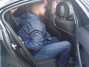zdjęcie kolorowe: zatrzymany pseudokibic siedzący w policyjnym radiowozie