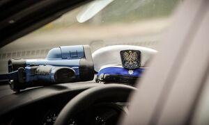 zdjęcie kolorowe: dwie policyjne czapki policjantów ruchu drogowego i urządzenie do pomiaru prędkości umieszczone na podszybiu radiowozu