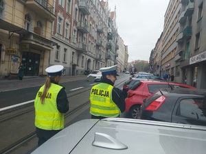 zdjęcie kolorowe: policjant i policjantka wydziału ruchu drogowego na katowickiej ulicy podczas zatrzymania samochodu do kontroli