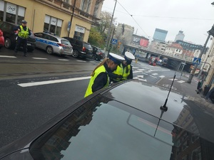 zdjęcie kolorowe: policjantka i policjant wydziału ruchu drogowego kontrolujący samochód