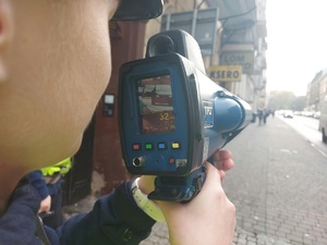 zdjęcie kolorowe: urządzenie do pomiaru prędkości z jaką jedzie samochód trzymane przez policjanta