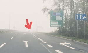 zdjęcie kolorowe: droga we mgle na której znajduje się prawie niewidoczny samochód z powodu nie włączonych świateł mijania