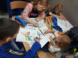 zdjęcie kolorowe: dzieci siedzące przy stoliku i kolorujące kolorowanki ze Sznupkiem podczas Turnieju Młodych Mistrzów w Ju-Jitsu Sportowym