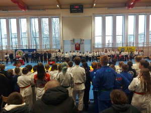 zdjęcie kolorowe: na sali gimnastycznej na której odbywał się Turniej Młodych Mistrzów w Ju-Jitsu Sportowym stoi policjanci, zawodnicy, organizatorzy i kibice