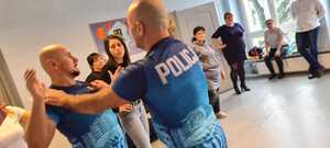 zdjęcie kolorowe: dwóch katowickich policjantów pokazujących jak obronić się przed atakiem napastnika