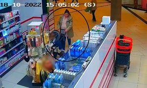 zdjęcie kolorowe: kobieta wchodząca z wózkiem dziecięcym do sklepu z kosmetykami