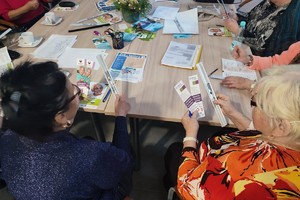 Zdjęcie kolorowe przedstawia uczestników spotkania podczas zapoznawania się z broszurami.