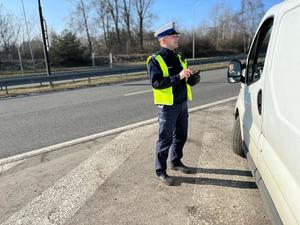 zdjęcie kolorowe: policjant katowickiej drogówki podczas rozmowy z kierującym zatrzymanym do kontroli drogowej