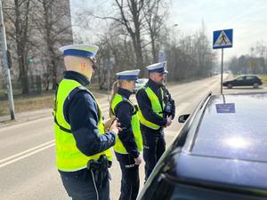 zdjęcie kolorowe: dwóch policjantów i policjantka z katowickiej drogówki podczas rozmowy z kierującym samochodem osobowym w trakcie działań &quot;Tempo 30&quot;