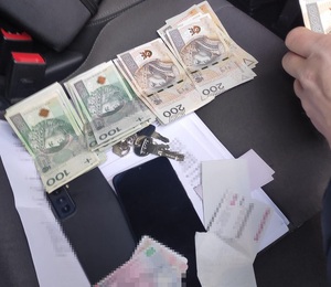 zdjęcie kolorowe; zabezpieczona gotówka i telefony komórkowe ułożone na fotelu samochodowym