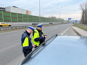 zdjęcie kolorowe: dwóch policjantów katowickiej drogówki podczas kontroli drogowej na autostradzie A4