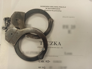 zdjęcie kolorowe: obwoluta teczki poszukiwawczej na której położono kajdanki