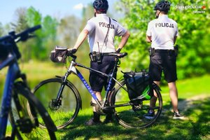 zdjęcie kolorowe: dwóch policjantów podczas patrolu rowerowego