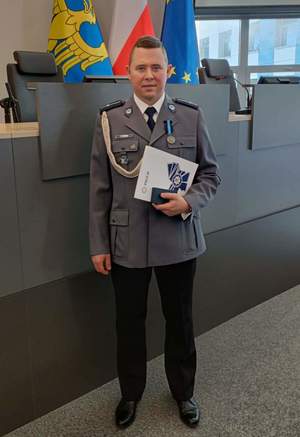 zdjęcie kolorowe: młodszy aspirant Tomasz Witański w umundurowaniu galowym w auli Komendy Wojewódzkiej Policji w Katowicach