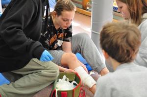 zdjęcie kolorowe: udzielanie pierwszej pomocy przedmedycznej pozorantowi z urazem nogi podczas Turnieju Bezpieczeństwa w Ruchu Drogowym