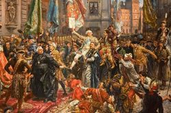 zdjęcie kolorowe: obraz Jana Matejki Konstytucja 3 Maja 1791 roku. Płótno przedstawia pochód posłów z Zamku Królewskiego do kolegiaty św. Jana w celu ponownego zaprzysiężenia wraz z królem tekstu konstytucji uchwalonej 3 maja 1791 przez Sejm Czteroletni (1788–1792). Pochód podąża ulicą Świętojańską wśród rozentuzjazmowanego tłumu mieszkańców Warszawy. Przejście ochraniają żołnierze prezentujący broń. W głębi, u wylotu ulicy Świętojańskiej na plac Zamkowy, widoczny jest fragment fasady Zamku Królewskiego z Wieżą Zygmuntowską (Zegarową).