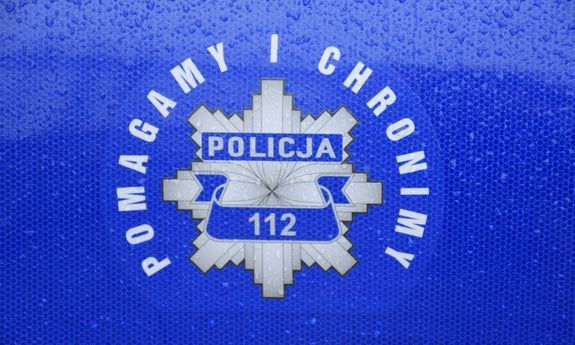 zdjęcie kolorowe: na niebieskim tle naklejka przedstawiająca policyjna odznakę i napis o treści policja 112 Pomagamy i chronimy