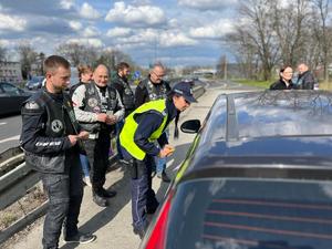 zdjęcie kolorowe: policjantka katowickiej komendy w towarzystwie motocyklistów ze stowarzyszenia „Moto Pistons Górny Śląsk” kontroluje samochód