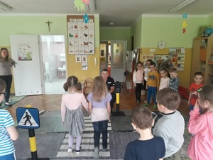 zdjęcie kolorowe: przedszkolaki podczas nauki prawidłowego przechodzenia przez przejście dla pieszych