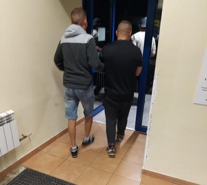 zdjęcie kolorowe: policjant z podejrzanym o włamania na korytarzu w komendzie