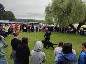 zdjęcie kolorowe: policyjny przewodnik psa służbowego podczas pokazu z posłuszeństwa psa służbowego wykonanego dla uczniów szkół podstawowych i ponadpodstawowych