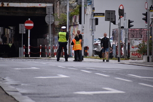 6 - zdjęcie kolorowe: policjant ruchu drogowego i służba porządkowa organizatora pilnujący bezpieczeństwa w rejonie tunelu