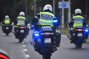 11 - zdjęcie kolorowe: policjanci ruchu drogowego jadący na służbowych motocyklach po trasie wyścigu