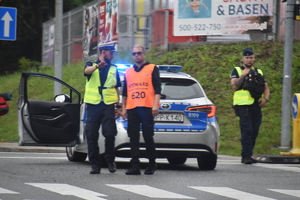 14 - zdjęcie kolorowe:  policjant ruchu drogowego i służba porządkowa rozmawiający o zabezpieczeniu trasy