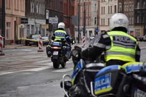 17 -  zdjęcie kolorowe: policjanci ruchu drogowego jadący na służbowych motocyklach po trasie wyścigu