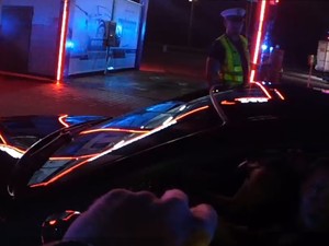 Zdjęcie kolorowe przedstawia policjanta ruchu drogowego podczas nocnej służby.