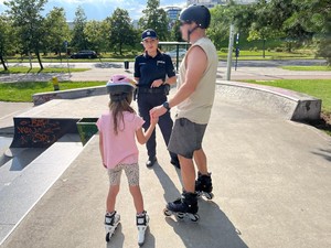 Zdjęcie kolorowe przedstawia policjanta podczas rozmowy z rodziną w skateparku.