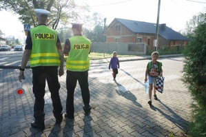 zdjęcie kolorowe: policjanci ruchu drogowego nadzorujący przejcie dzieci przez przejście dla pieszych