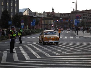 Zdjęcie kolorowe przedstawia policjantów kierujących ruchem pojazdów na skrzyżowaniu.