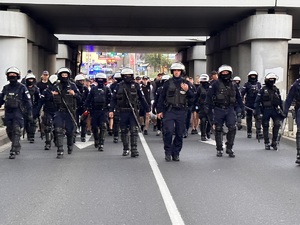 zdjęcie kolorowe: policjanci oddziału prewencji w asyście kroczącej prowadzą kibiców na stadion