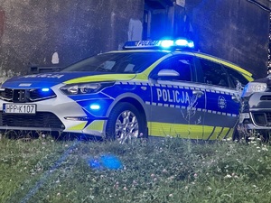 zdjęcie kolorowe: policyjny radiowóz zabezpieczający przemarsz kibiców