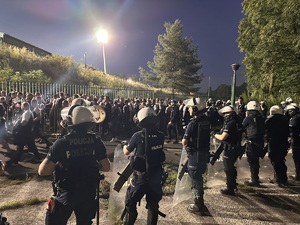 zdjęcie kolorowe: policjanci oddziału prewencji w asyście kroczącej i kibice przy bramie wejściowej na katowicki stadion